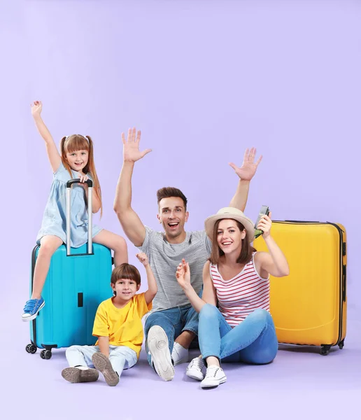 Familia feliz con el equipaje en el fondo de color — Foto de Stock