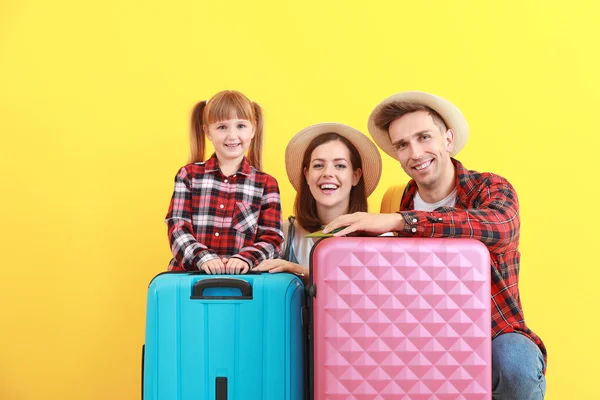 Glückliche Familie mit Gepäck auf farbigem Hintergrund — Stockfoto