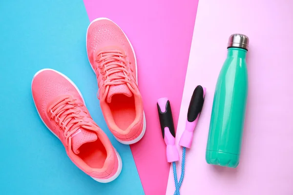 Sportvatten flaska, skor och hopprep på färg bakgrund — Stockfoto