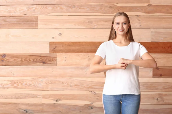 Young deaf mute woman using sign language on wooden background — Stock Photo, Image