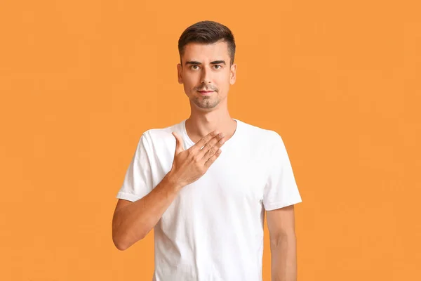 Young deaf mute man using sign language on color background — Stock Photo, Image