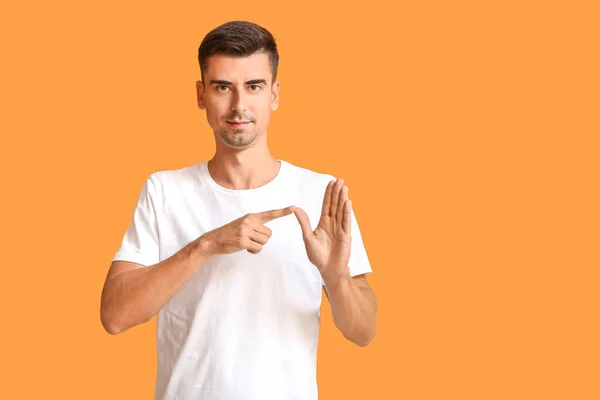 Junger taubstummer Mann benutzt Zeichensprache auf farbigem Hintergrund — Stockfoto