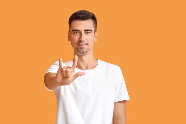 Young deaf mute man using sign language on color background — Stock Photo, Image