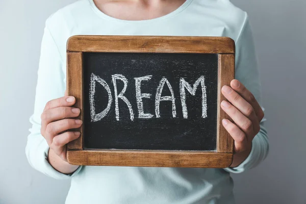 Woman with word DREAM written on chalkboard against grey background, closeup — Stock Photo, Image