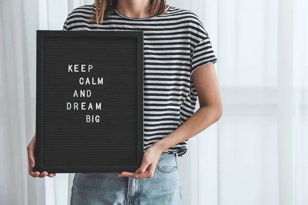 Woman holding board with motivation phrase indoors