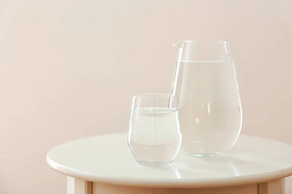 Склянка і глечик з прісною водою на столі на світлому фоні — стокове фото