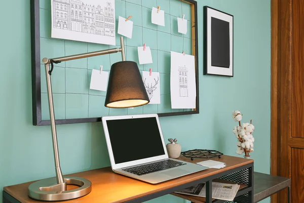 Bekväm arbetsplats med stämningsbräda och laptop nära färgvägg — Stockfoto
