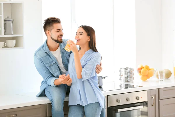 Hermosa pareja joven bebiendo jugo en la cocina en casa — Foto de Stock