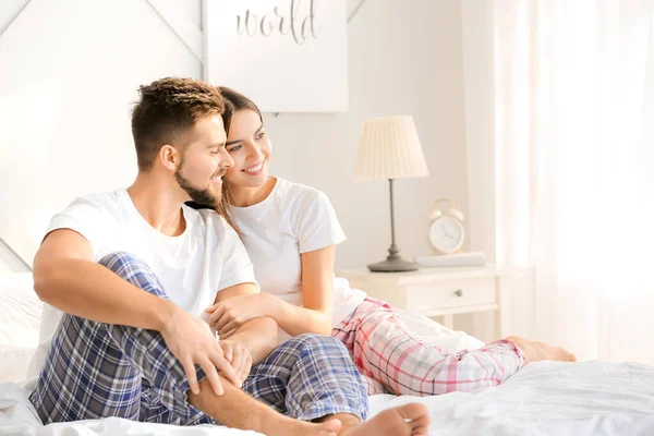 Belo jovem casal sentado na cama em casa — Fotografia de Stock