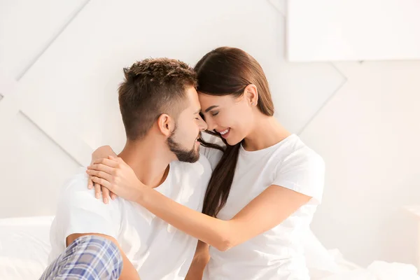 Beautiful young couple sitting on bed at home — Stock Photo, Image