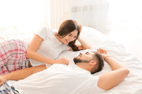 Happy young couple lying on bed at home — ストック写真