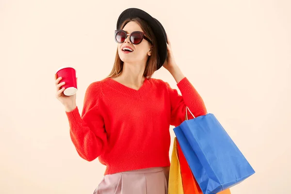 Mulher bonita com sacos de compras e café no fundo de cor — Fotografia de Stock