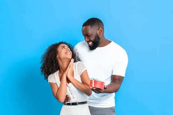 Portret van Afro-Amerikaanse man cadeau te geven aan zijn vriendin op kleur achtergrond — Stockfoto