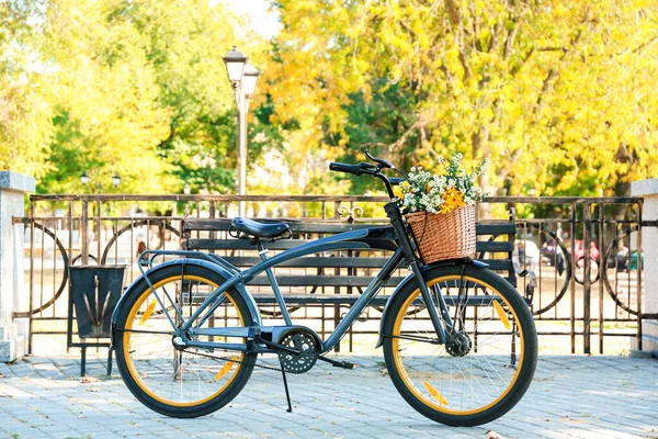 Bicicleta moderna con cesta y ramo de flores en la calle de la ciudad — Foto de Stock