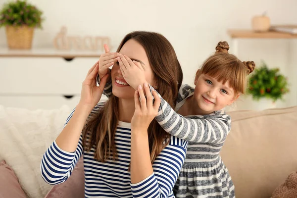 Szczęśliwa dziewczyna zakrywa oczy swojej matki w domu — Zdjęcie stockowe