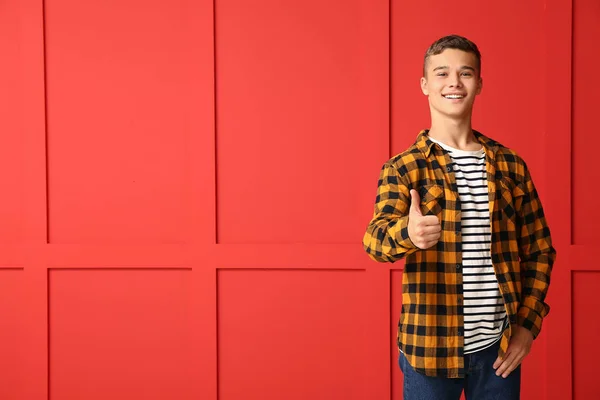 Cool tizenéves fiú mutatja hüvelykujj-up a színes háttér — Stock Fotó