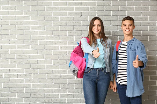 Portrait of teenagers showing thumb-up on brick background — Stock Photo, Image