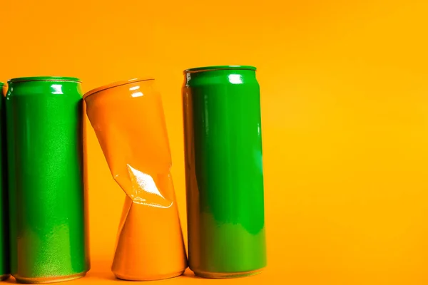 Crumpled lata de laranja entre os verdes em fundo de cor. Conceito de singularidade — Fotografia de Stock