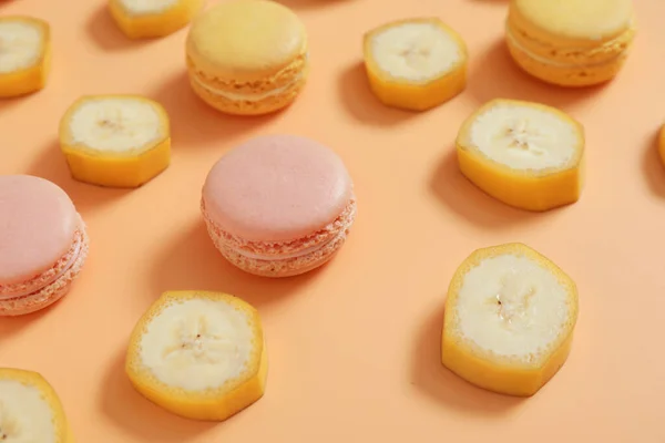 Tasty macarons with banana slices on color background — Stock Photo, Image