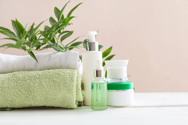 Beyaz masadaki havlularla kozmetik ürünleri — Stok fotoğraf