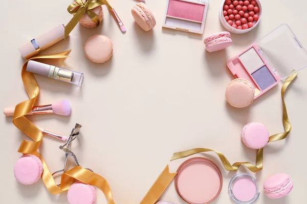 Frame gemaakt van lekkere macarons met make-up cosmetica op lichte ondergrond — Stockfoto