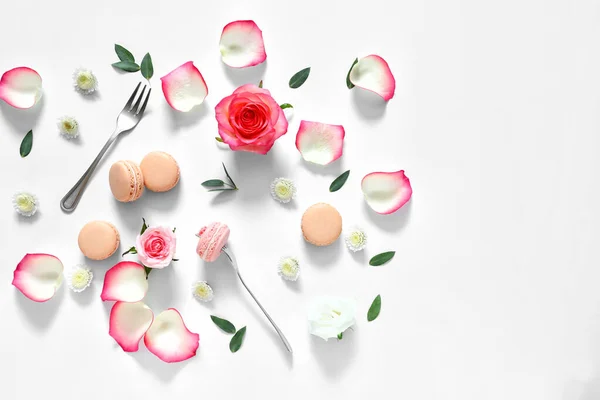 Smaklig makaroner med ros blommor på vit bakgrund — Stockfoto