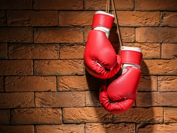 Boxing gloves hanging on brick wall — Stock Photo, Image