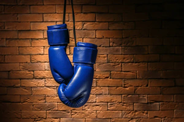 Pair of boxing gloves hanging against brick wall — Stock Photo, Image