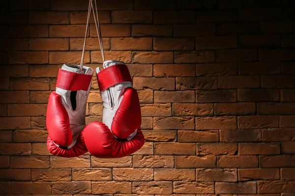 Par de luvas de boxe penduradas contra a parede de tijolo — Fotografia de Stock