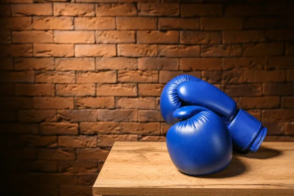 Par de guantes de boxeo en la mesa contra la pared de ladrillo — Foto de Stock