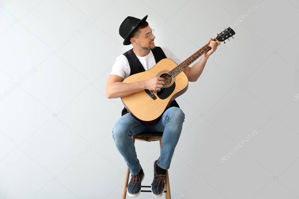 Handsome man playing guitar on light background