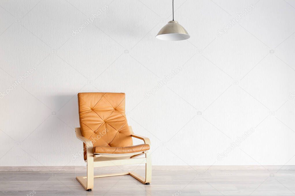 Stylish armchair with lamp near white wall