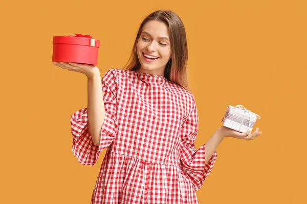 Beautiful woman with gift boxes on color background — Stok fotoğraf