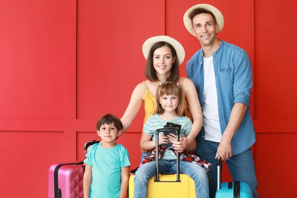 Happy family with luggage on color background — Stock Photo, Image