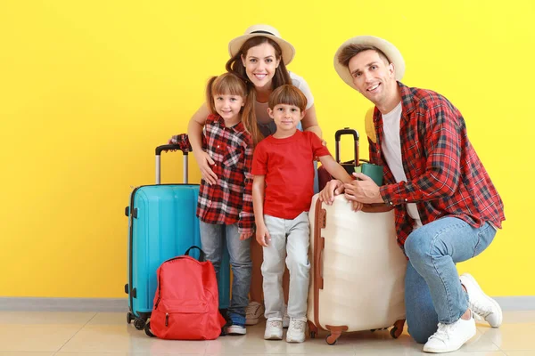Familia feliz con equipaje cerca de la pared de color — Foto de Stock