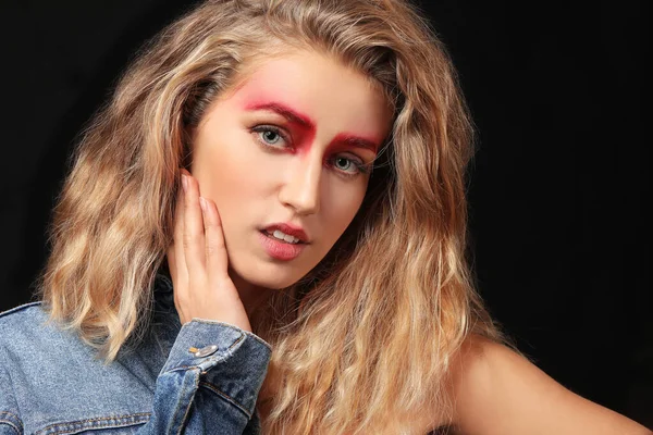 Mujer joven con cejas creativas sobre fondo oscuro — Foto de Stock