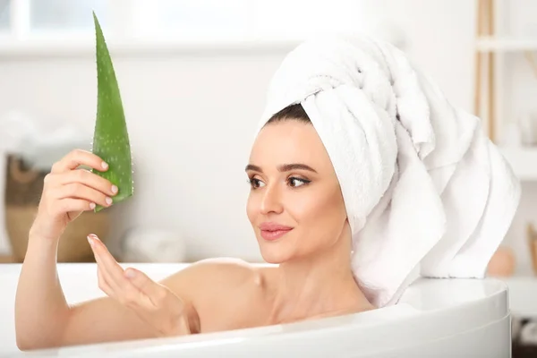 Schöne junge Frau mit Aloe Vera im Badezimmer — Stockfoto