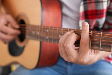 Evde gitar çalan yakışıklı adam, yakın plan.