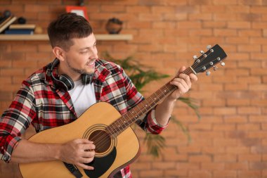 Yakışıklı adam evde gitar çalıyor.