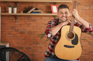 Evde gitar çalan yakışıklı bir adam.