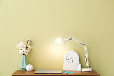 Renk duvarının yanında lamba ve saatle modern stil işyeri