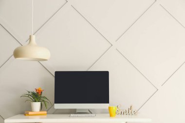 Gri duvarın yanında bilgisayarı olan modern stil işyeri