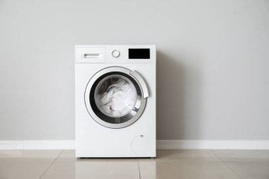 Beyaz duvarın yanında çamaşır makinesi olan modern bir çamaşır makinesi.