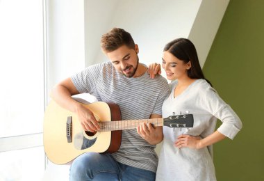Evde gitar çalan güzel genç bir çift.