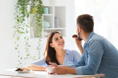 Mutfakta kurabiyelerle kahve içen mutlu genç çift.