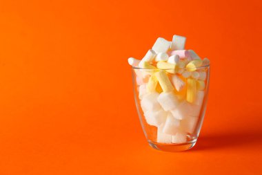 Marşmelovlu cam ve renkli arkaplanda şeker