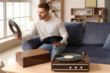 Genç adam evde pikapla müzik dinliyor.