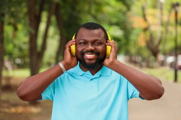 Handsome African-American man listening to music outdoors — Stock Photo, Image