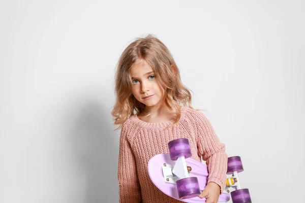 Cute little girl with skateboard on light background — Stock Photo, Image