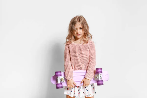 Cute little girl with skateboard on light background — Stock Photo, Image